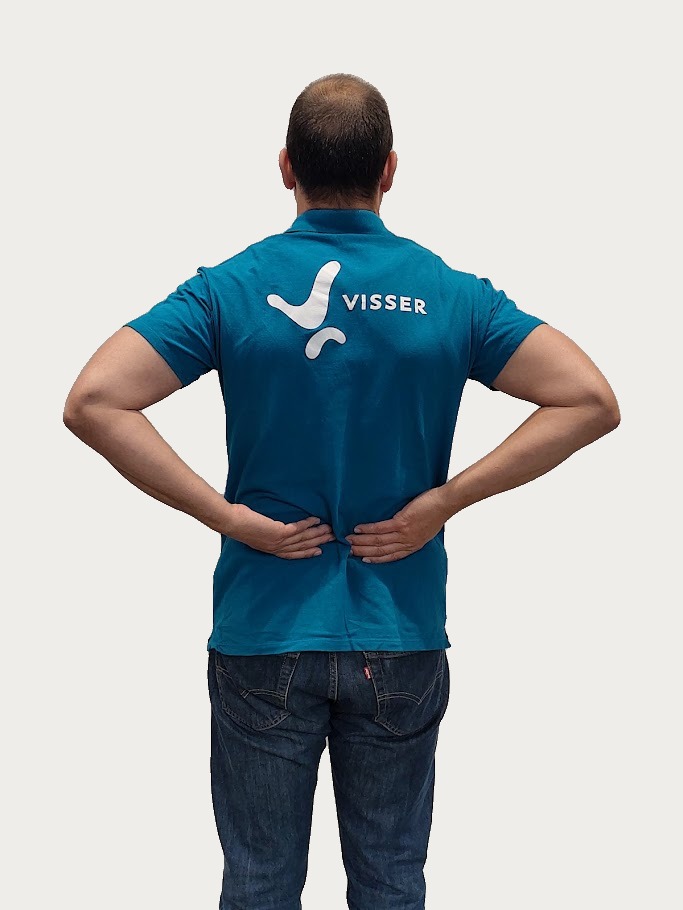 Man met blauwe polo met het woord 'VISSER' op de rug, die zijn handen op zijn onderrug plaatst, wat duidt op onderrugpijn.