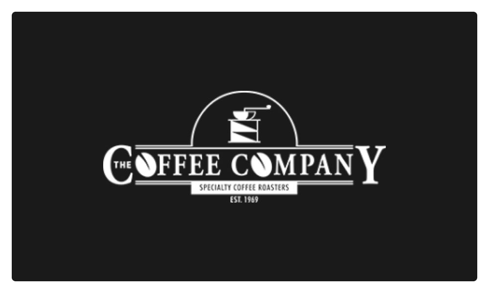 Logo of The Coffee Company featuring a vintage coffee grinder icon with text 'Specialty Coffee Roasters Est. 1969' on a black background.