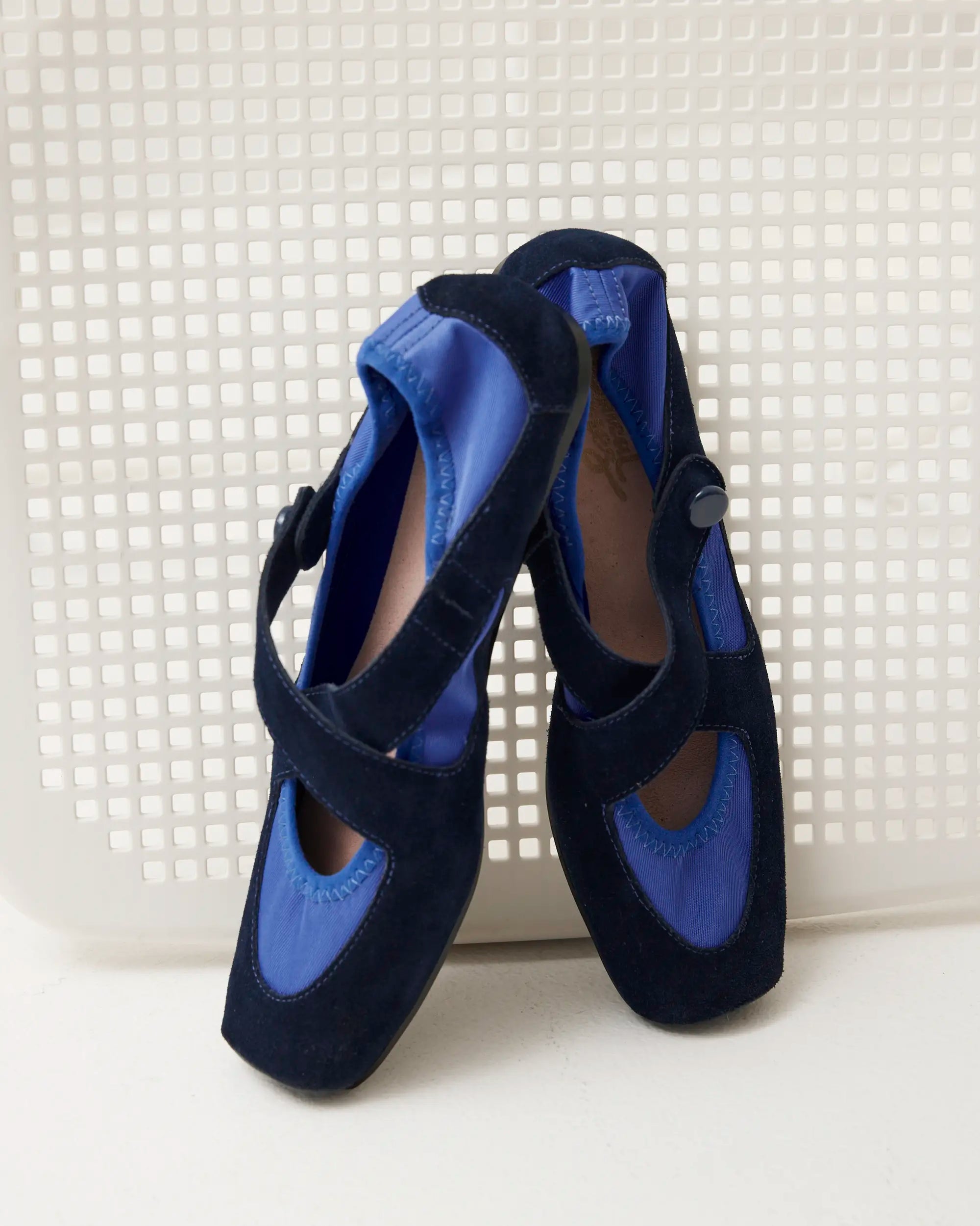 Pair of navy suede flats against a textured backdrop