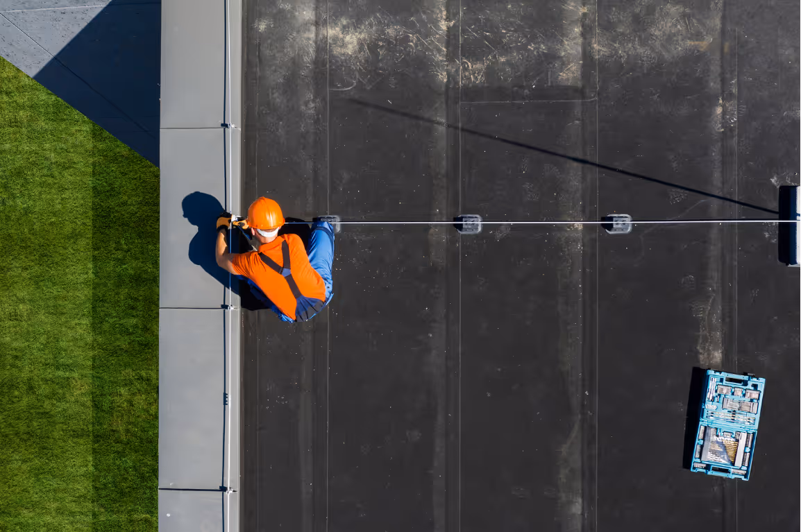Mann arbeitet auf Hausdach und verlegt Kabel