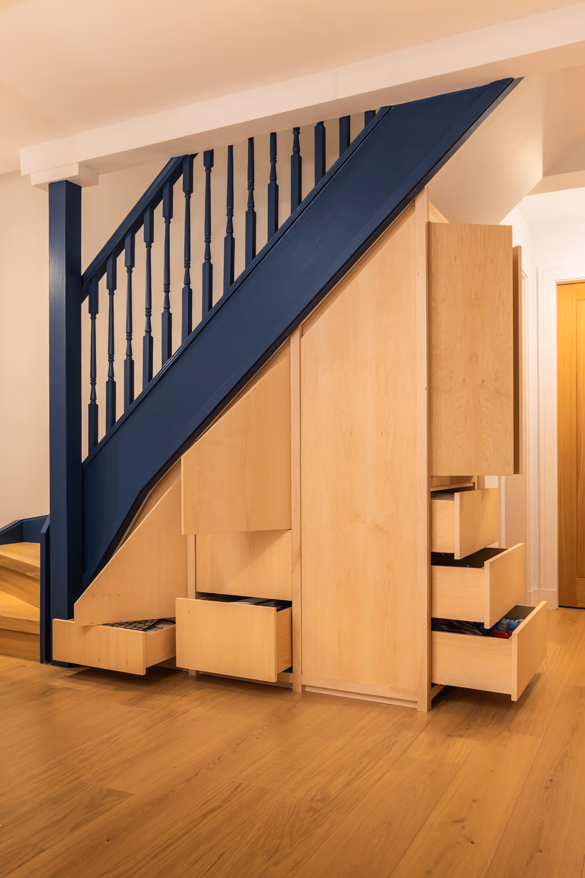 Photograph of bespoke under-stair storage with a number of open drawers
