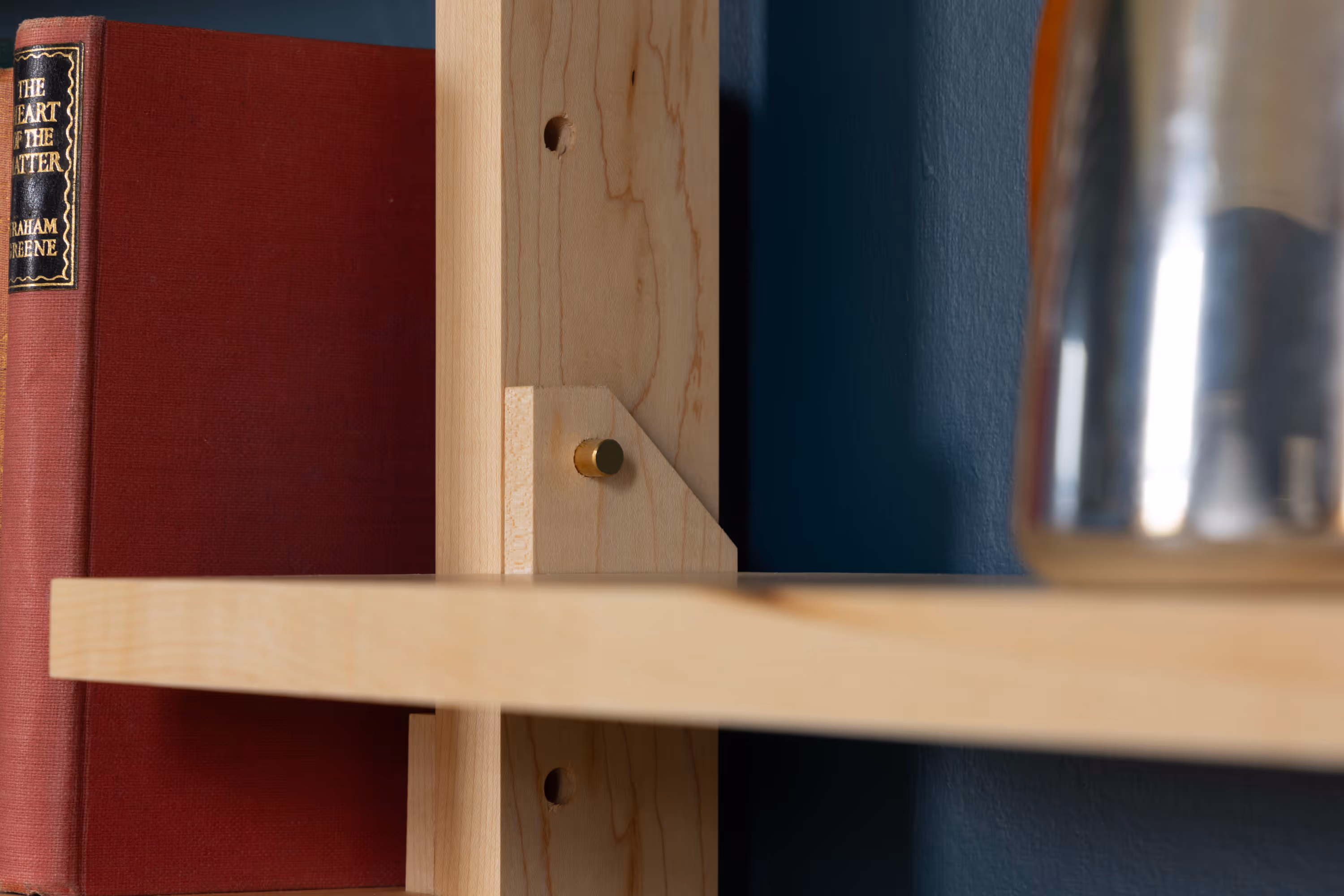 A close-up on the side of a Forma shelf, showing the brass pin that attaches it to the bay.