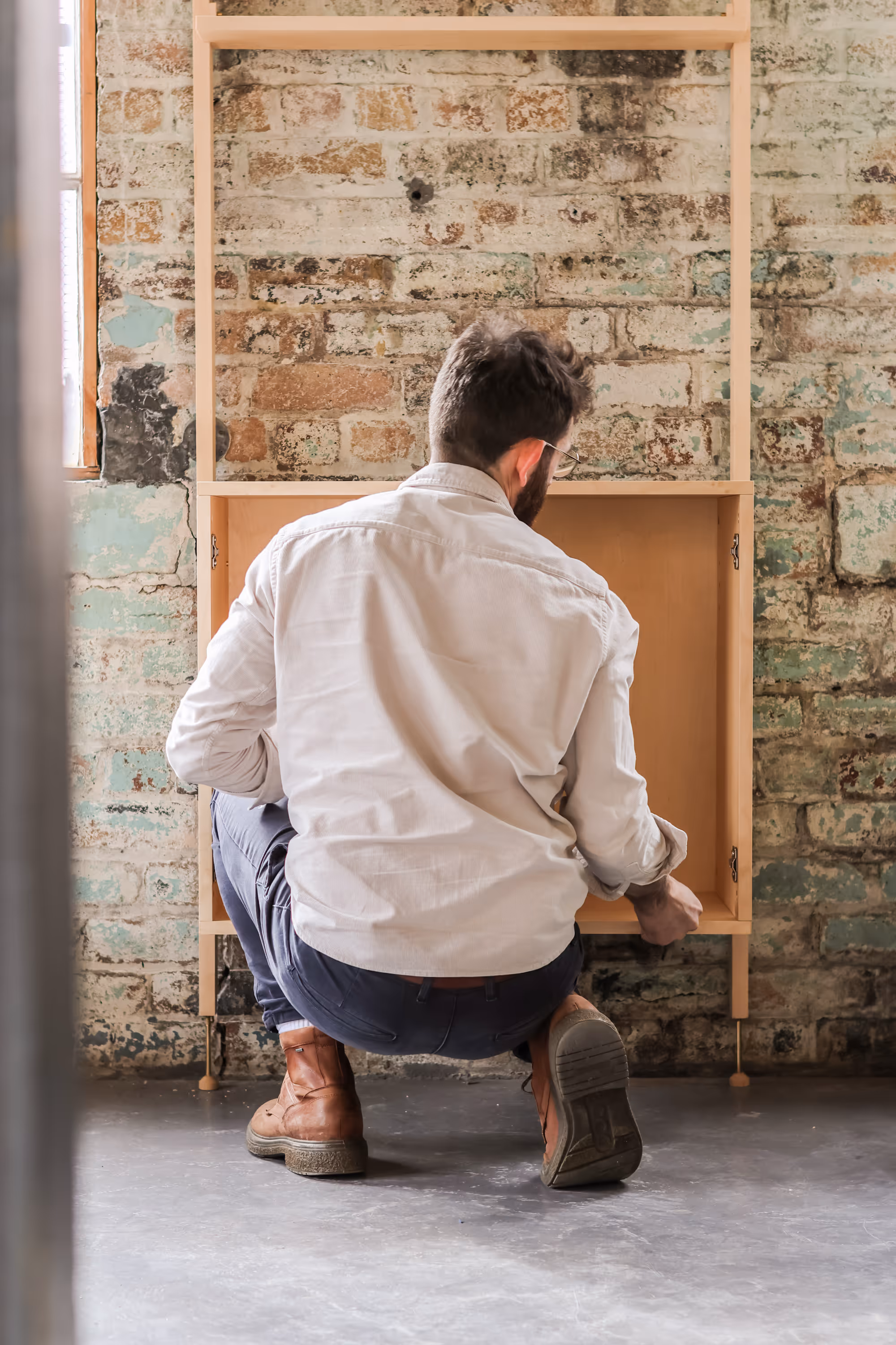A man fitting a cabinet in place in a Forma shelving unit