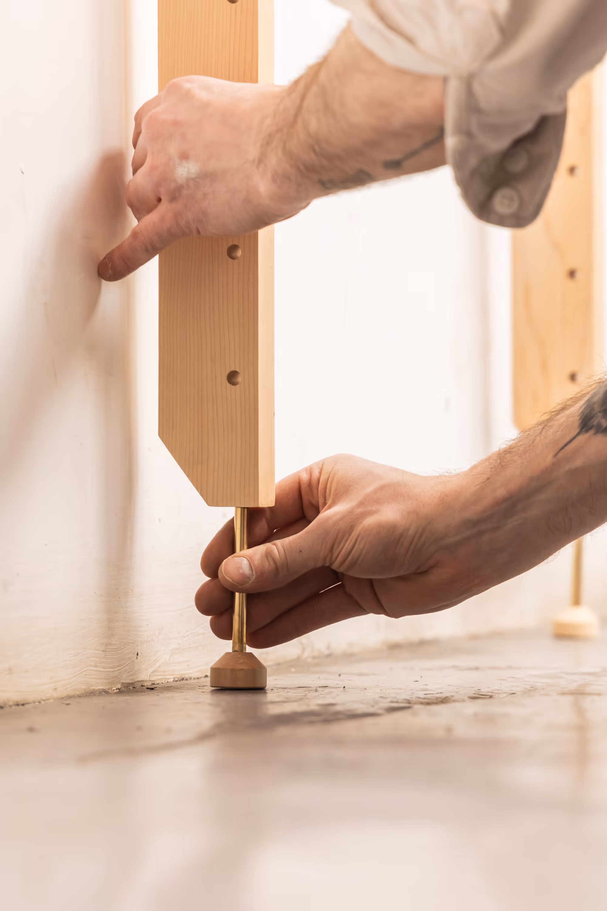 Photograph of the foot of a Forma shelving unit bay, being adjusted by two hands