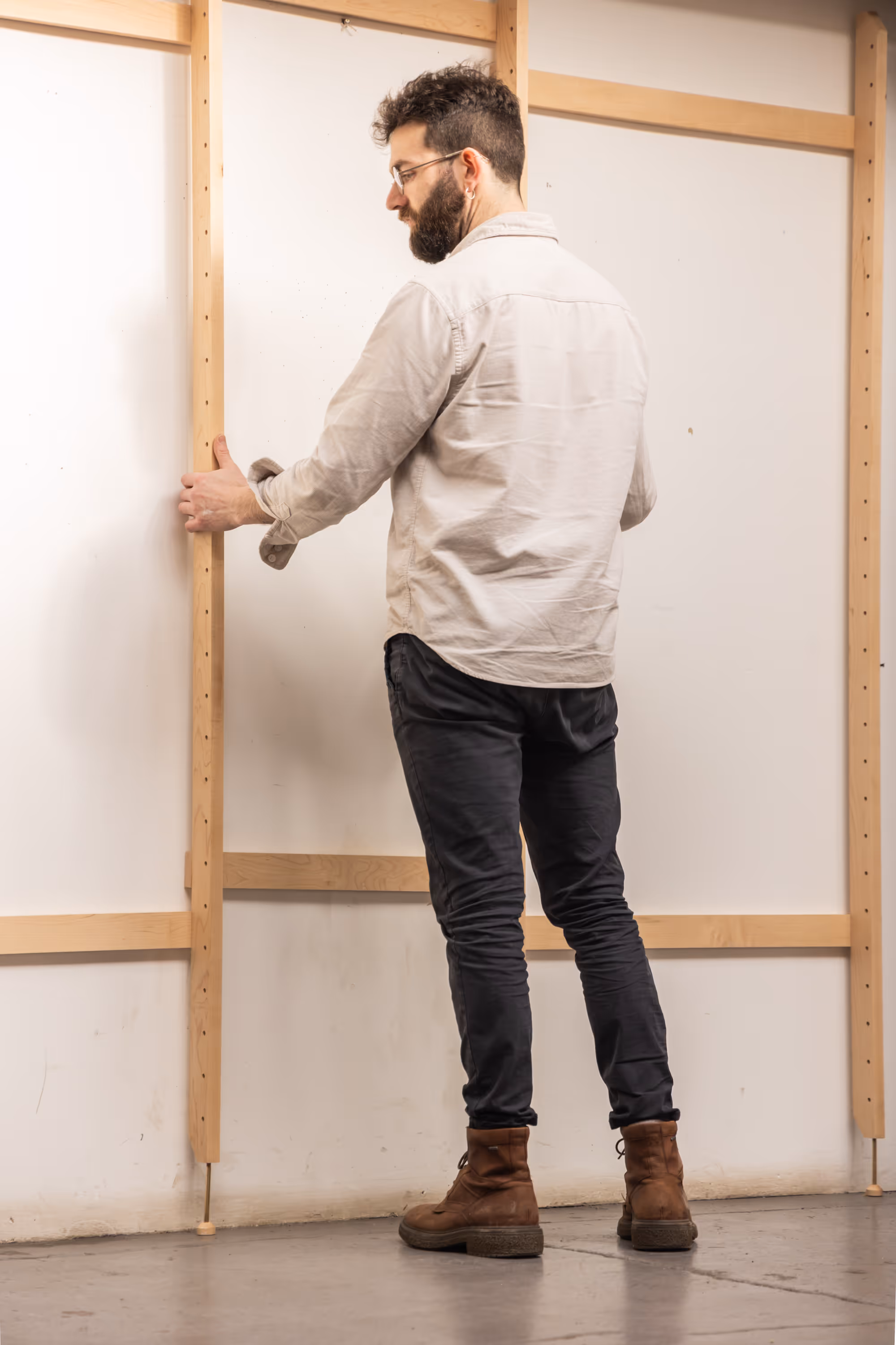 A man standing, assembling a Forma shelving unit