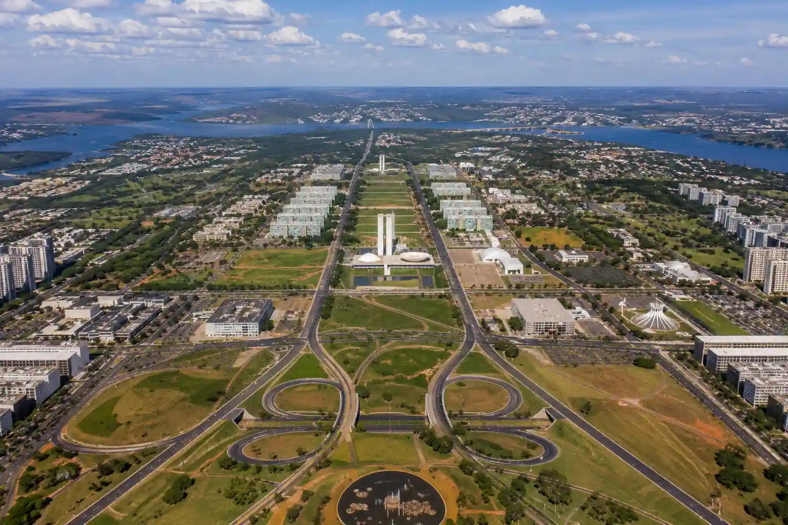 A high-altitude aerial view of Brasília showcasing the Monumental Axis, government buildings, wide avenues, and the city's unique urban design.