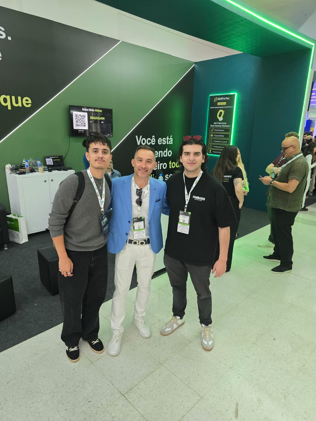 	Three men posing together in front of an iSellForYou "Make More Money" stand