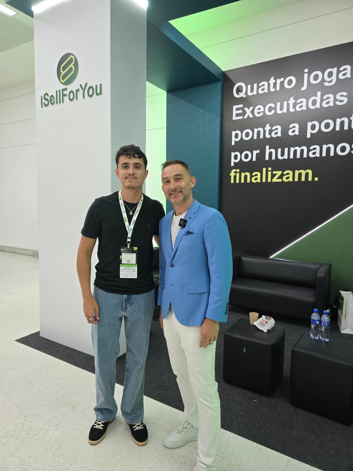 Two men posing in front of the iSellForYou wall