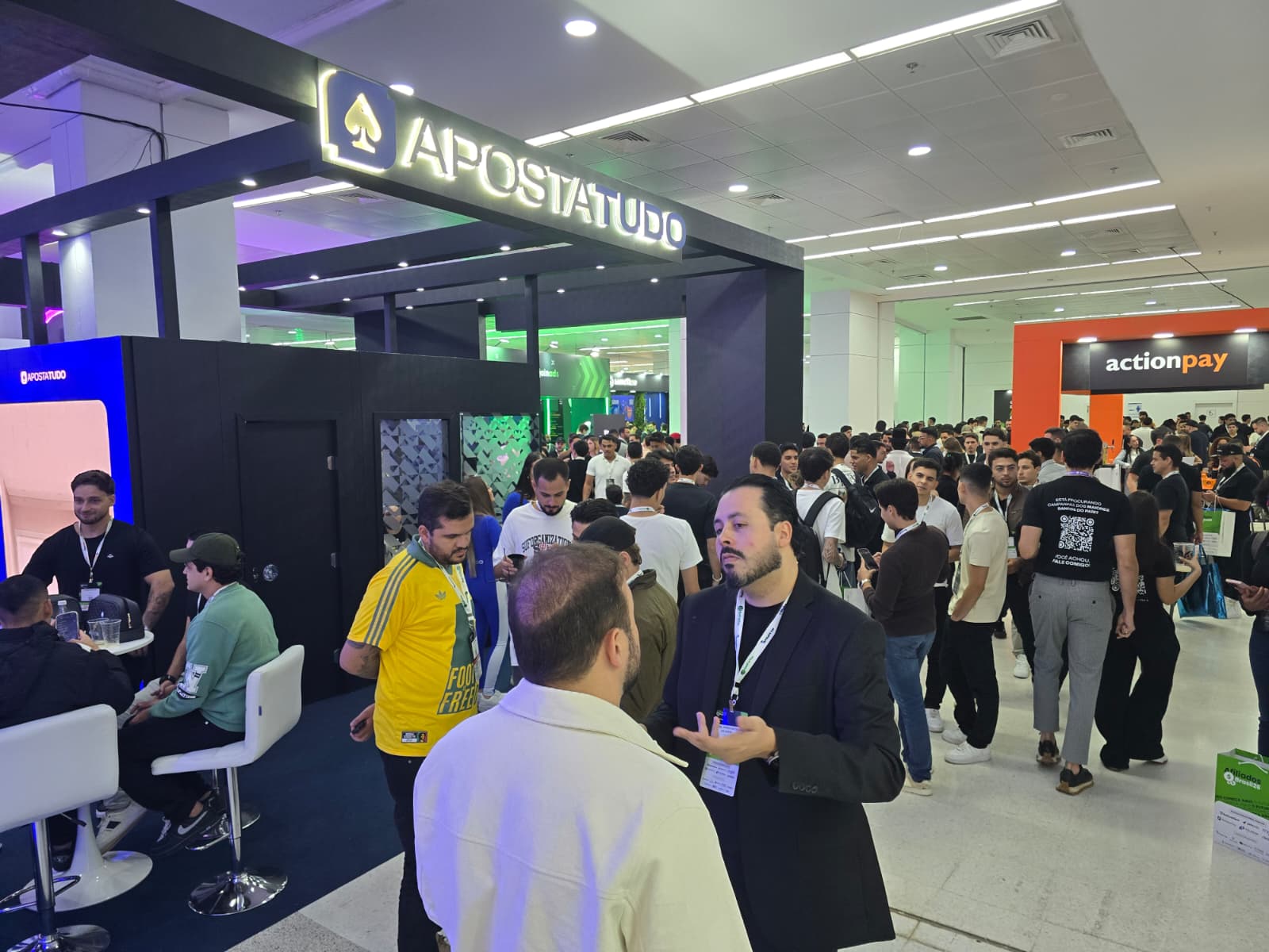 Crowded expo hall with the ApostaTudo and actionpay booths