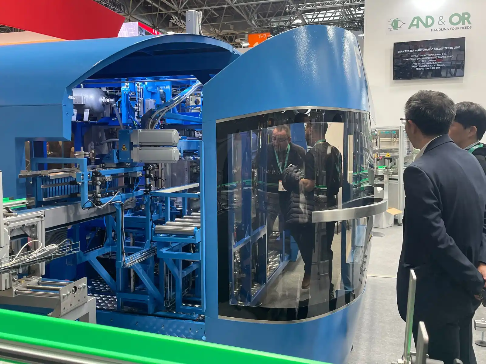 Máquina industrial de grande porte apresentada durante a K-Messe 2025, observada por visitantes no estande de exposição.