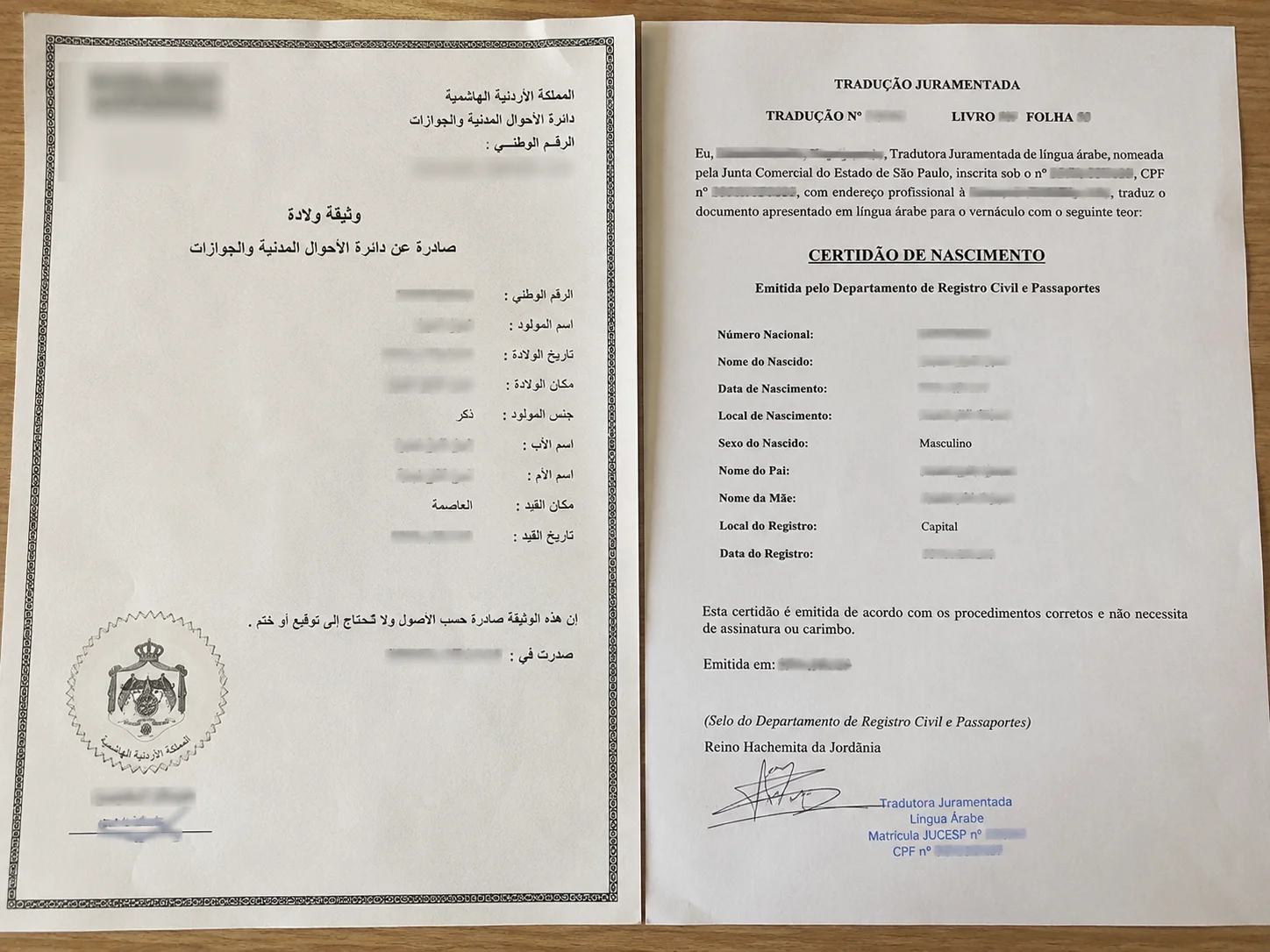 Certidão de nascimento em árabe ao lado de sua tradução juramentada para o português, com documentos oficiais, carimbos e assinaturas sobre uma mesa de madeira.