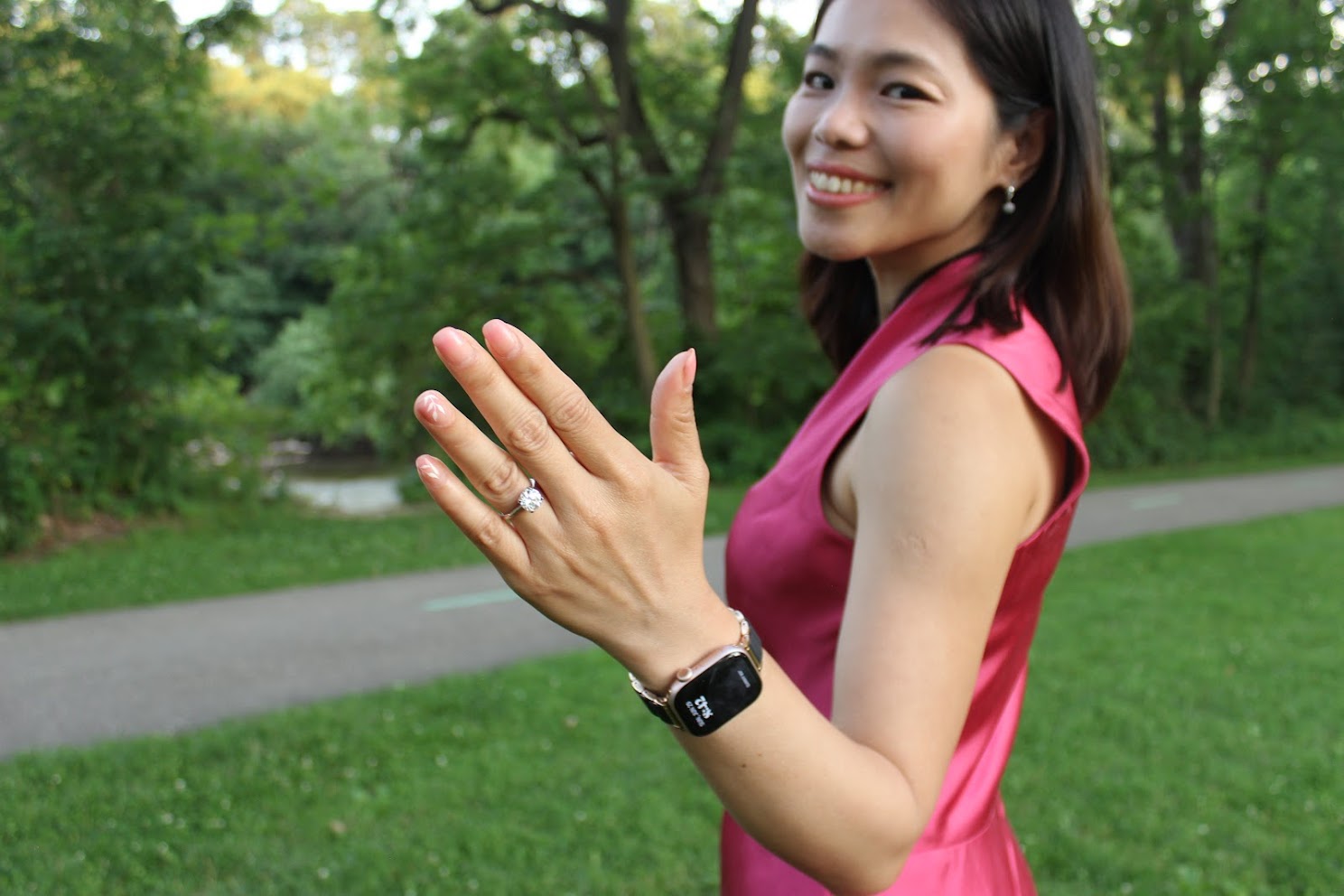 Diem holiding out her ring while wearing a pink dress