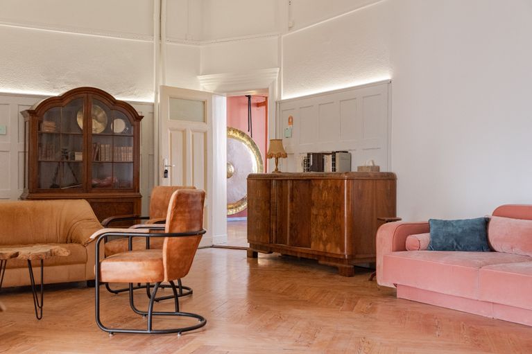 Lounge der Kulturvilla mit Sofas und Holzboden