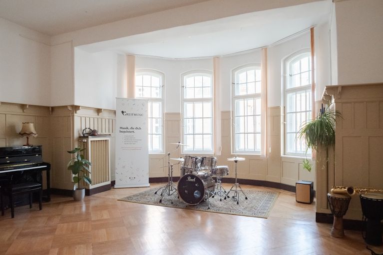 Flügelsaal mit großen Fenstern und Musikinstrumenten