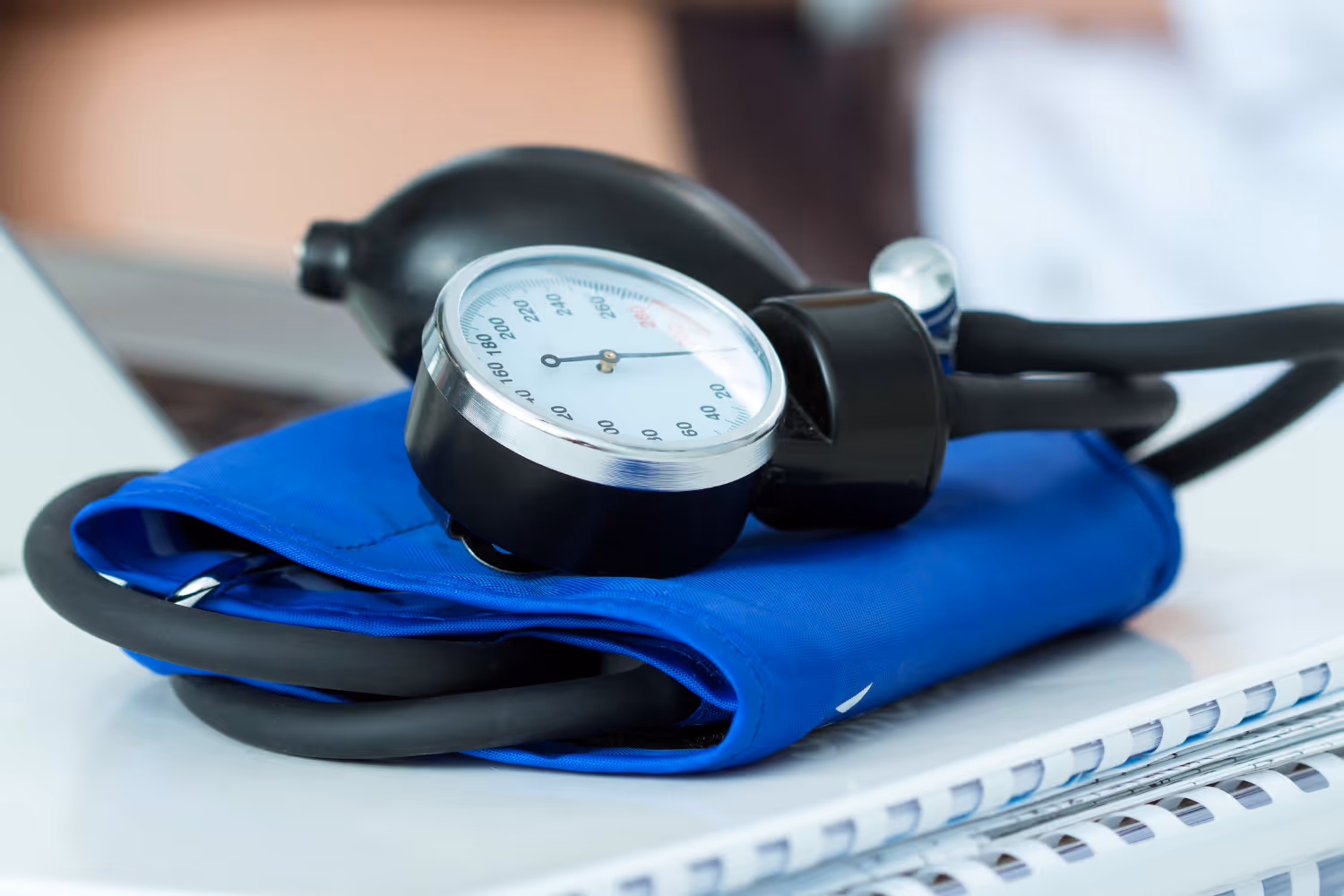Close-up of a blood pressure monitor with a blue cuff on a white surface.