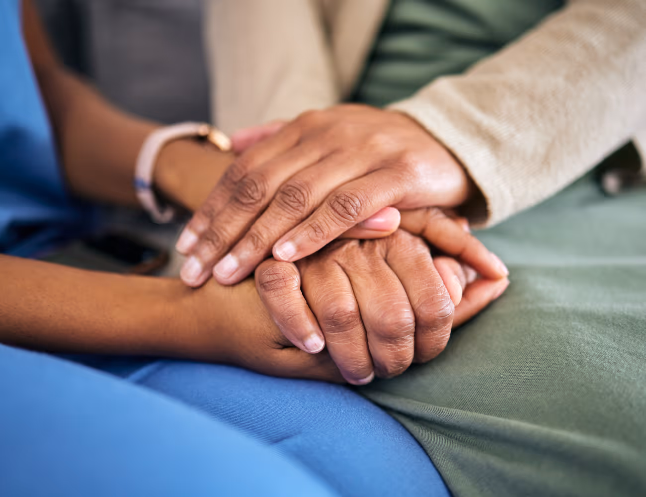 Close-up of two people holding hands in a comforting gesture.