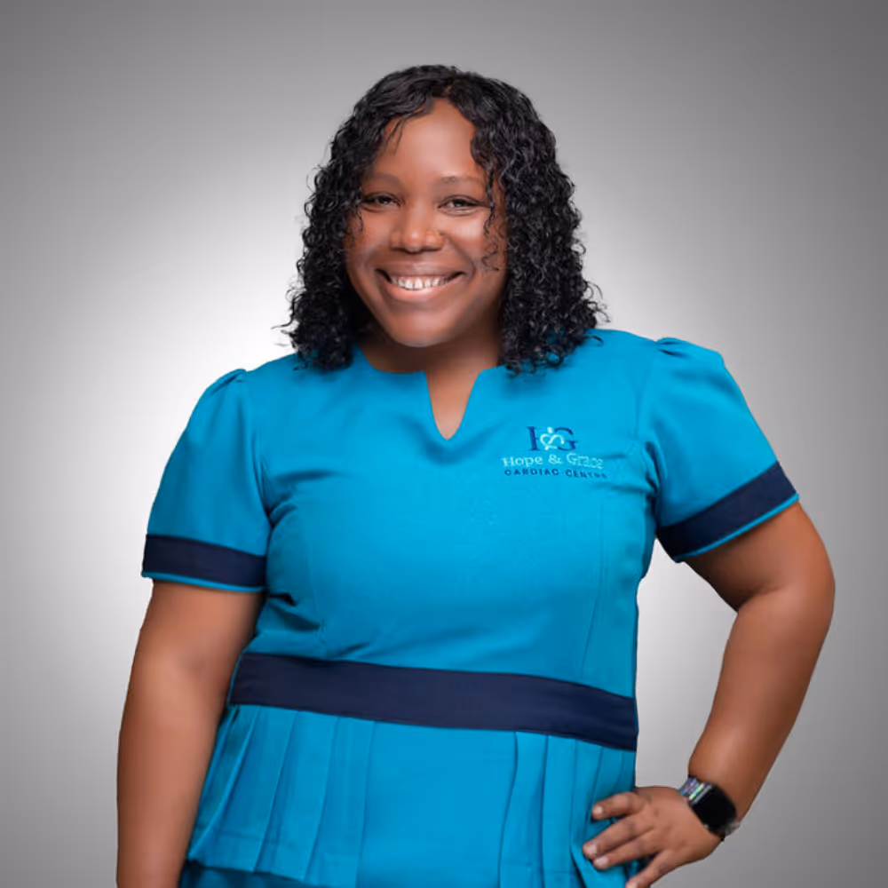 Smiling woman in teal medical scrubs with Hope & Grace Cardiac Center logo on chest, hand on hip.