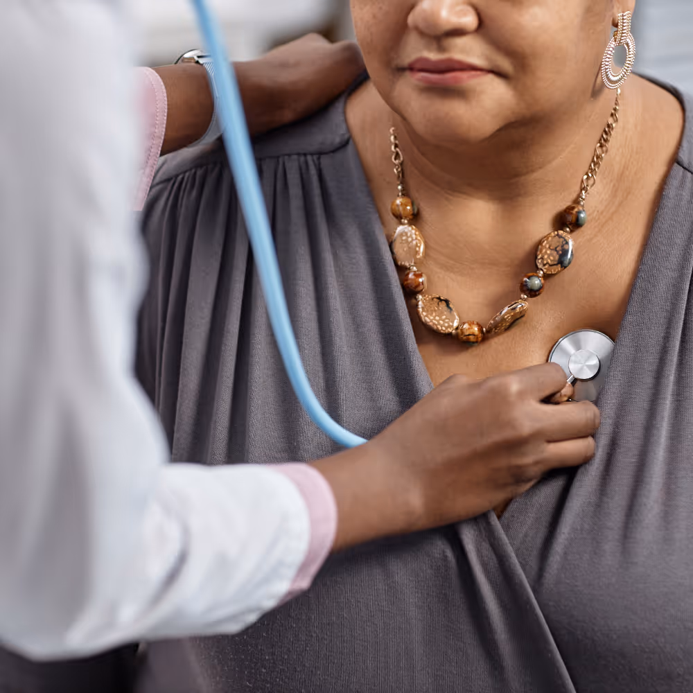 Doctor using stethoscope to listen to a woman's heart during a checkup.
