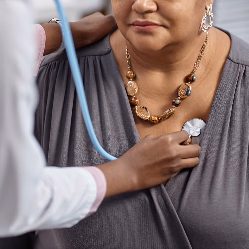 Doctor using a stethoscope on a woman's chest during a medical checkup.