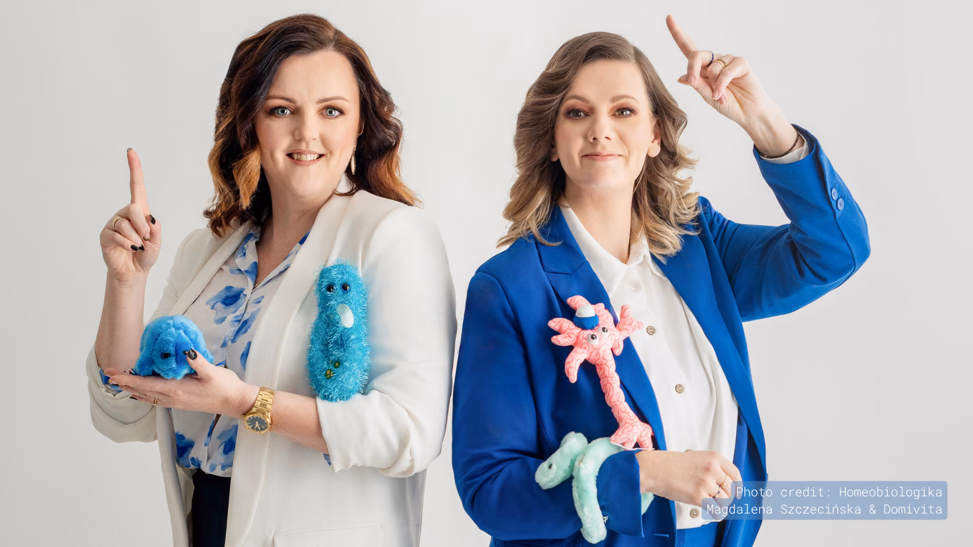 Two wellness experts holding plush microbe toys