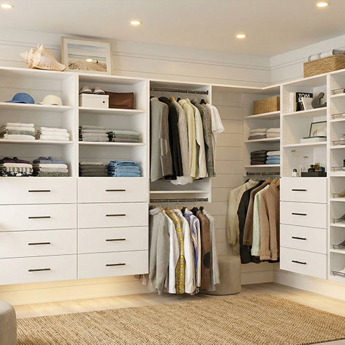 Custom modular closet system with white wood finishes and brushed nickel hardware in a Nantucket guest suite.