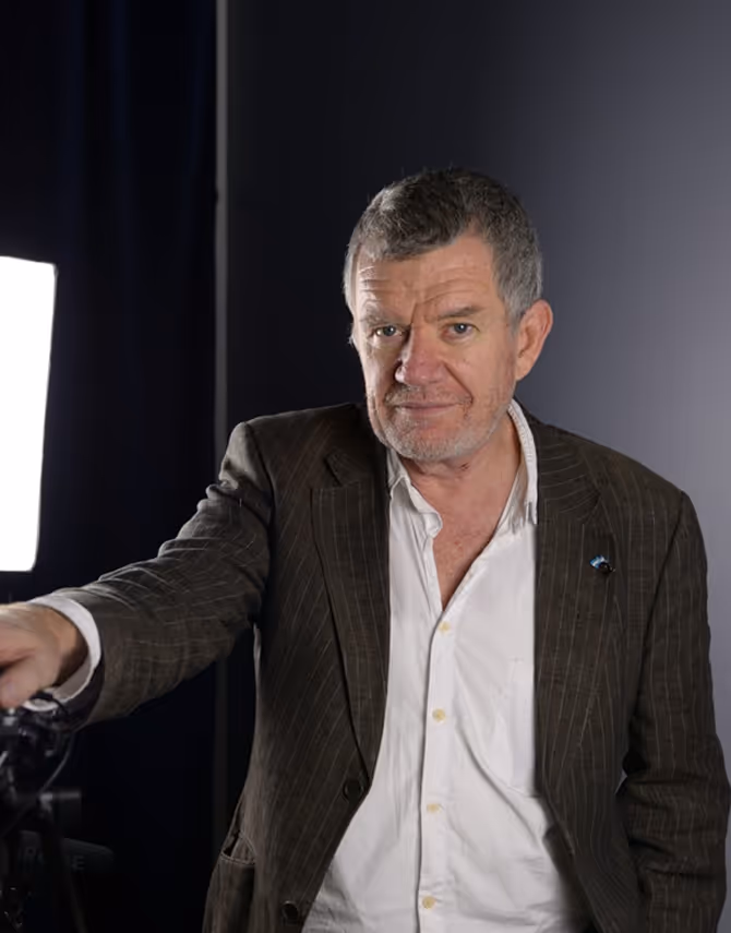 Middle-aged man in pinstripe jacket against dark studio background