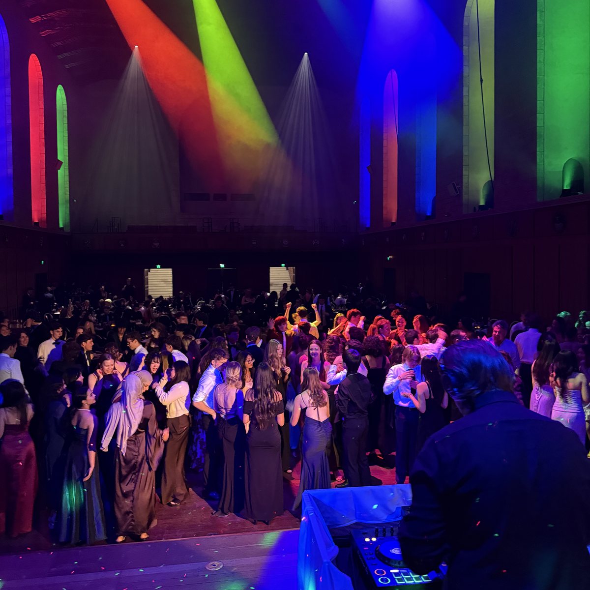 Packed dance floor under coloured beam lighting at a university ball in Winthrop Hall, UWA, Perth