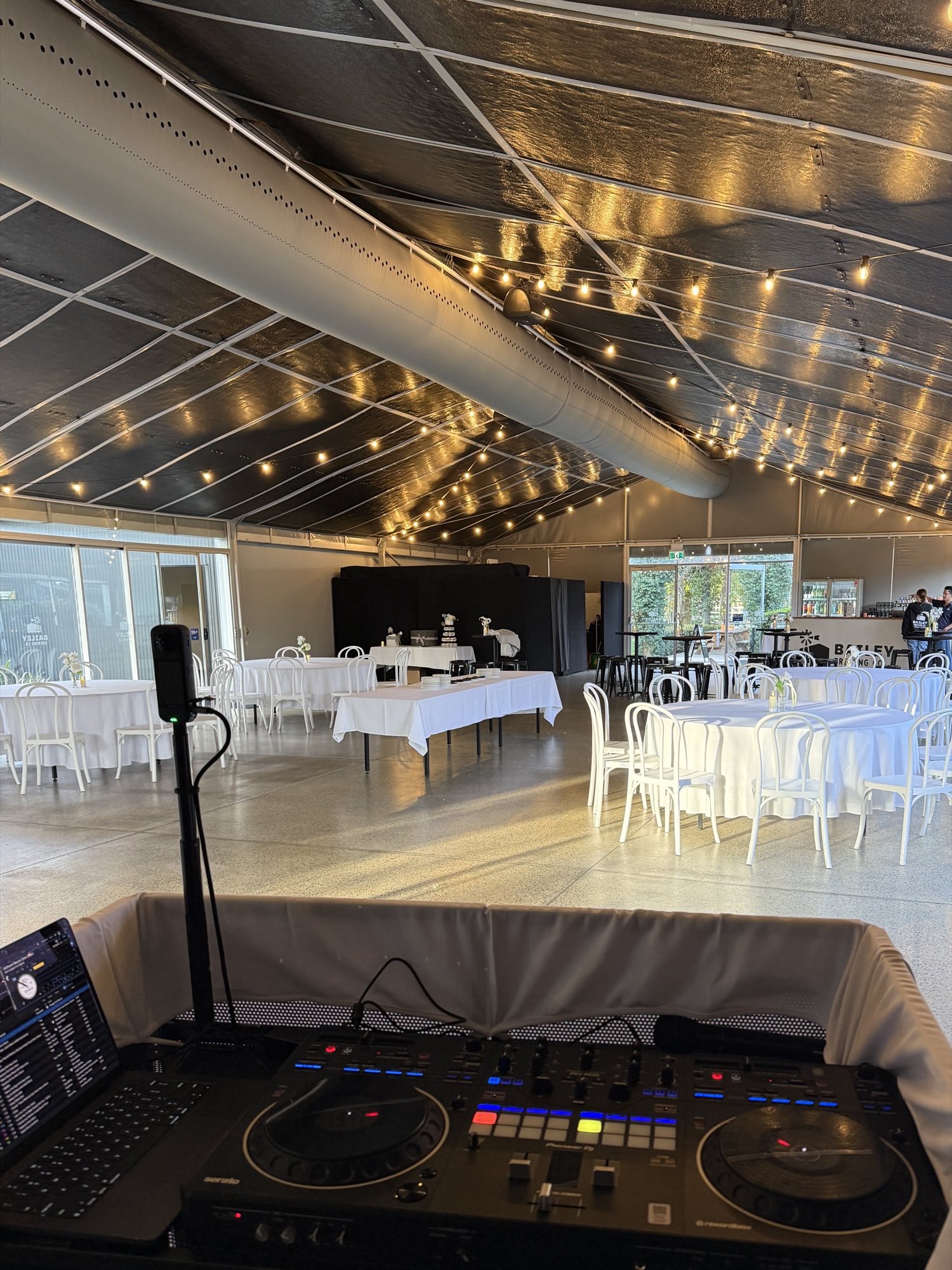 Certified Entertainment DJ booth and sound system set up before a Perth wedding reception, with festoon lighting and set tables