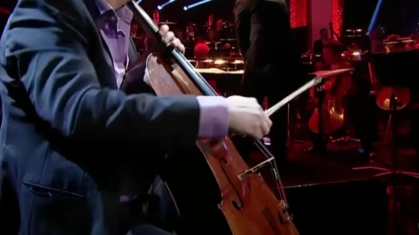 Close-up of a cellist performing on stage with an orchestra