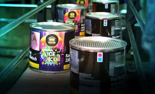 A row of cans of ice cream on a conveyor belt.