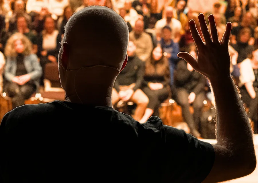 Speaker auf der Bühne vor vollem Saal beim Live-Event