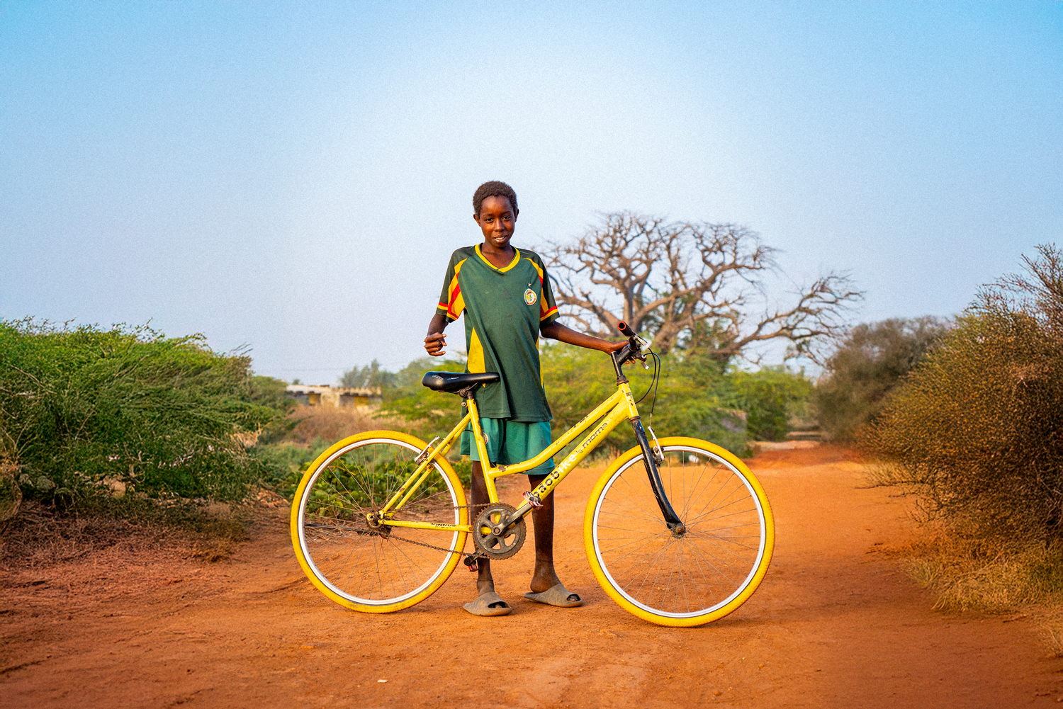 Student riding yellow Baobike bicycle on rural road in Senegal