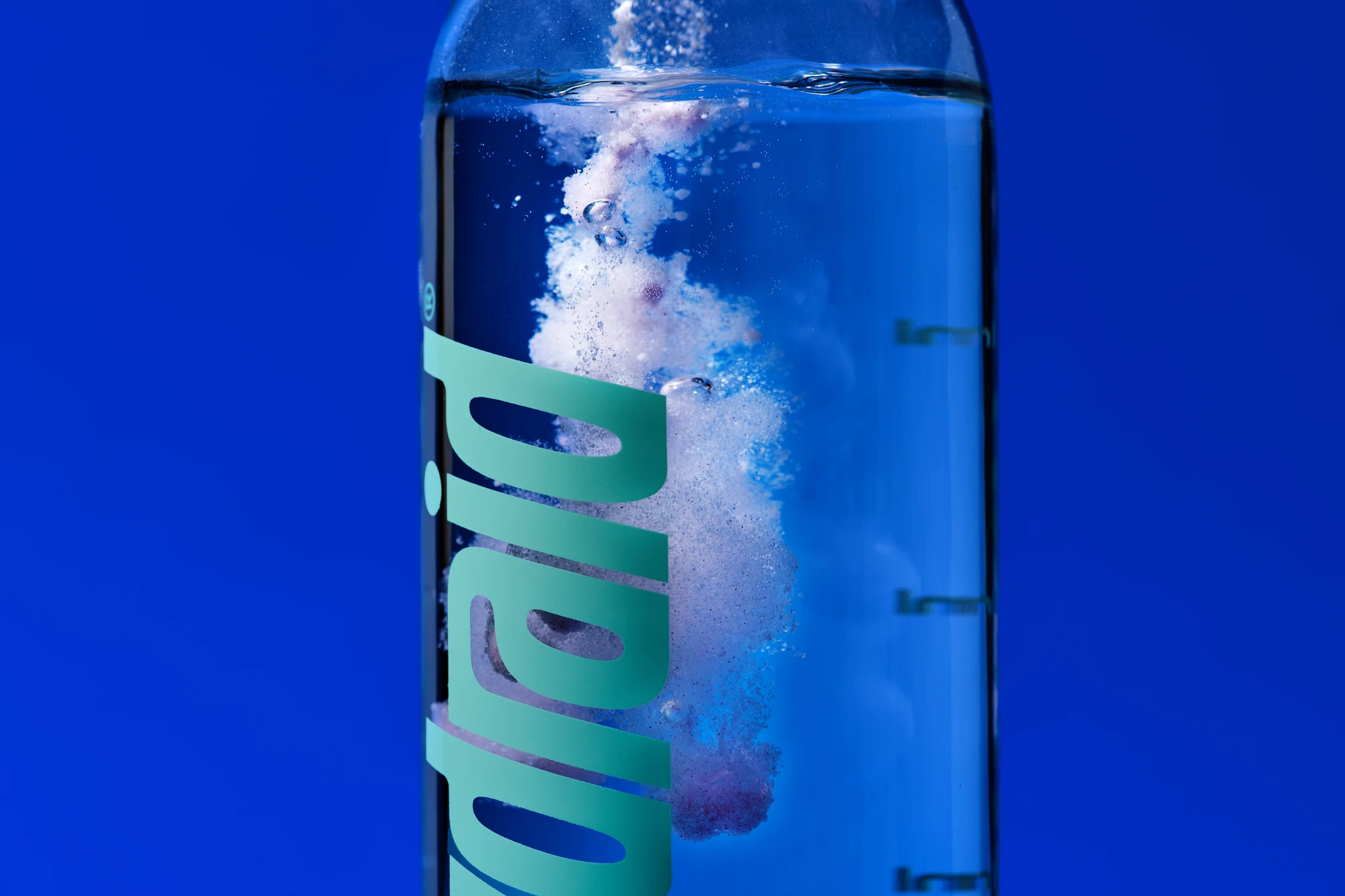 Makrofotografie für Hydraid: Nahaufnahme der Flasche mit sprudelndem Elektrolytpulver im Wasser Macro photography for Hydraid: close-up of the bottle with fizzing electrolyte powder in water