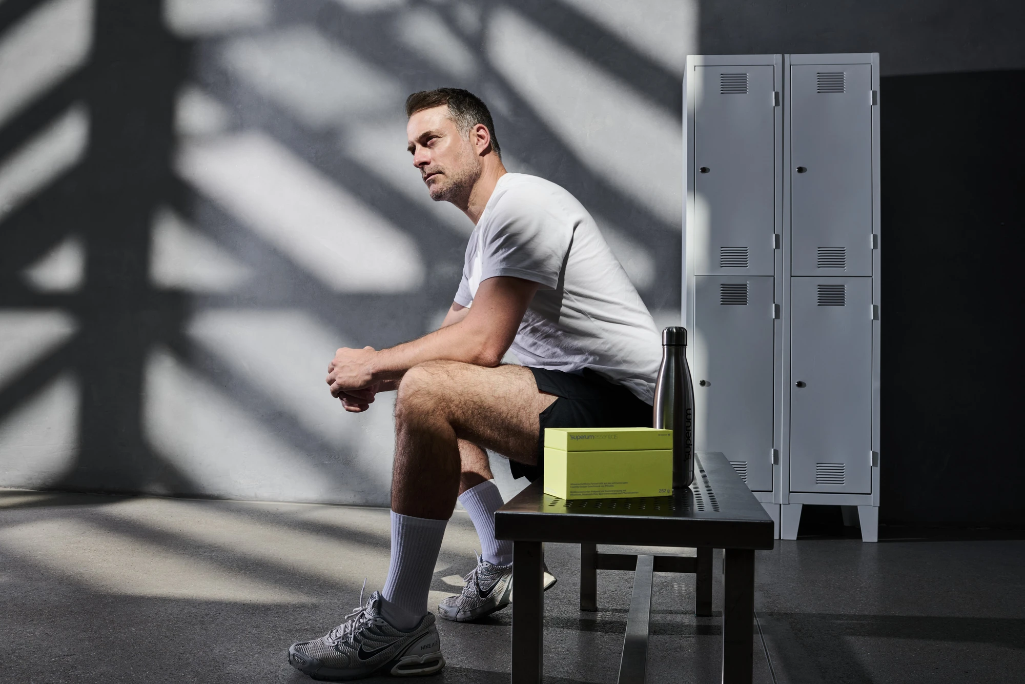 Kampagnenfotografie für Superum: Mann in der Umkleidekabine neben Produktbox und Trinkflasche | Campaign photography for Superum: man in a locker room next to the product box and water bottle