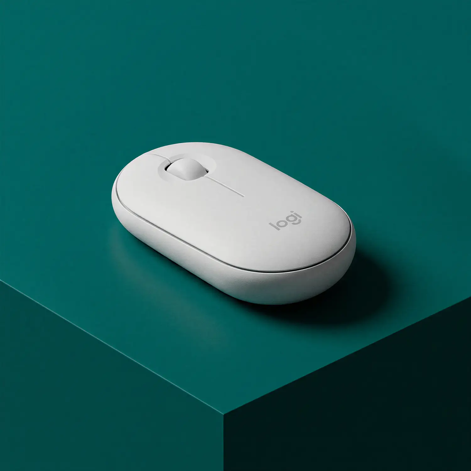 White wireless Logitech computer mouse on a dark teal surface.