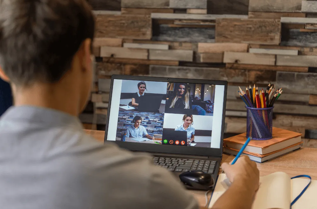 An employee is video conferencing with his team through a laptop.