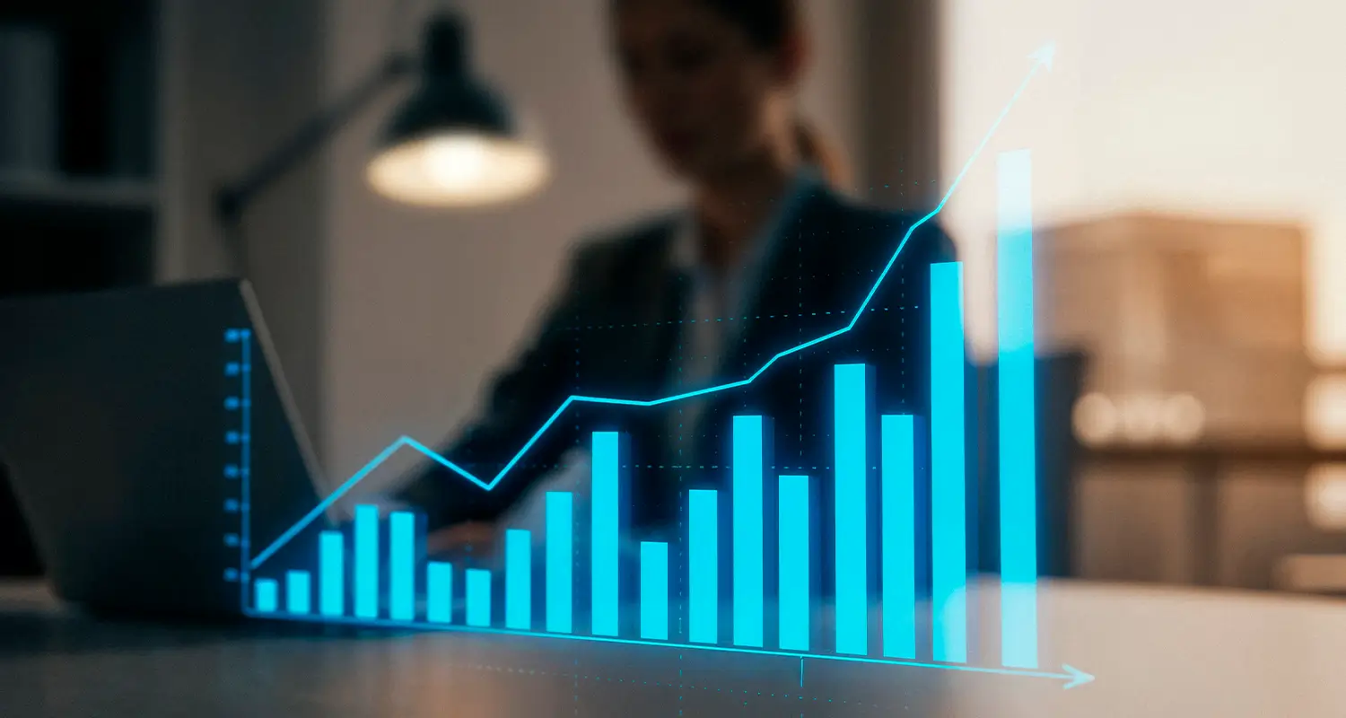 A glowing 3D holographic bar chart with an upward-trending line overlaid in cyan blue floats in the foreground, while a blurred business executive works on a laptop in a warmly lit office background. The visualization represents accelerating revenue growth and sales performance scaling through BPO outsourcing strategies.