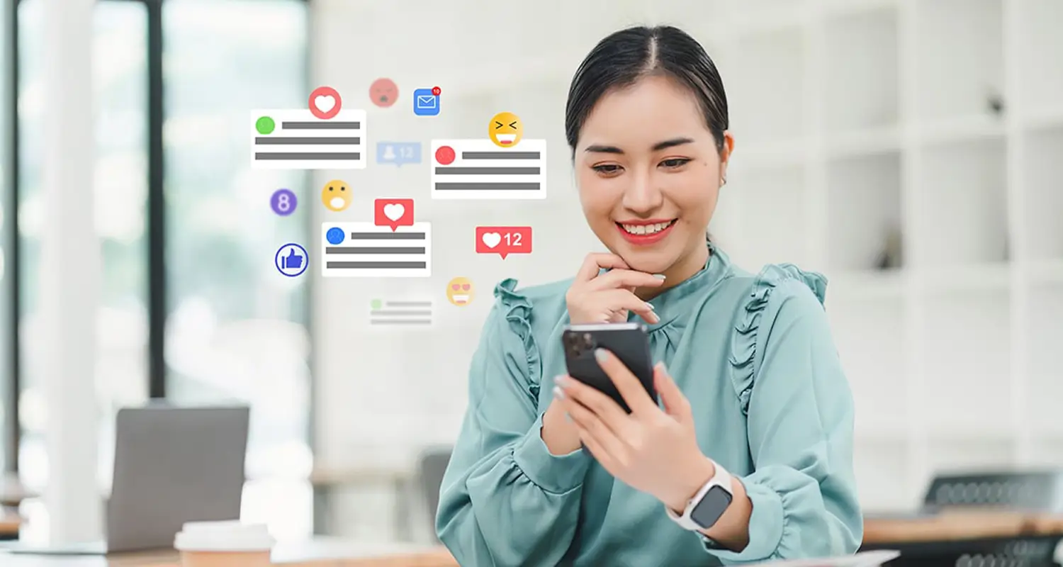 Young woman smiling at her smartphone surrounded by floating social media notification icons including likes, emojis, and message alerts