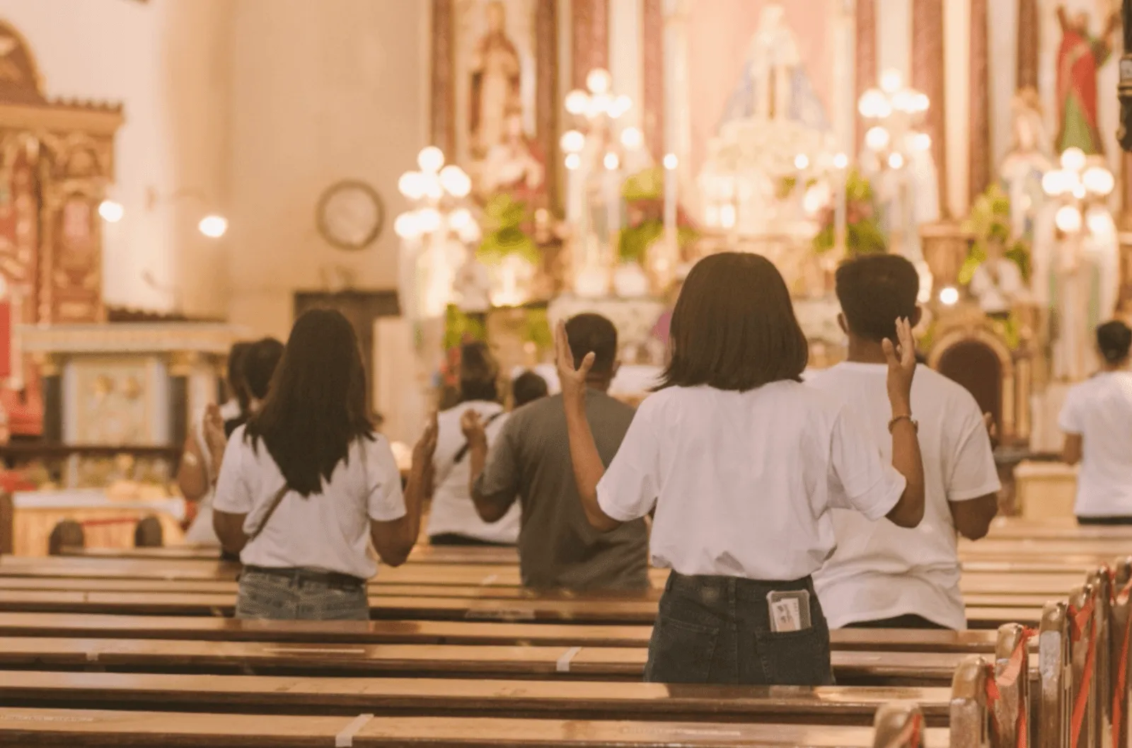 Catholic Filipinos attend mass inside a church, standing by the pews in song during Holy Week.