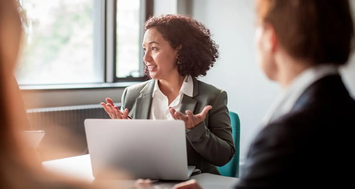 Operations manager gestures expressively while presenting strategy to colleagues at a conference table