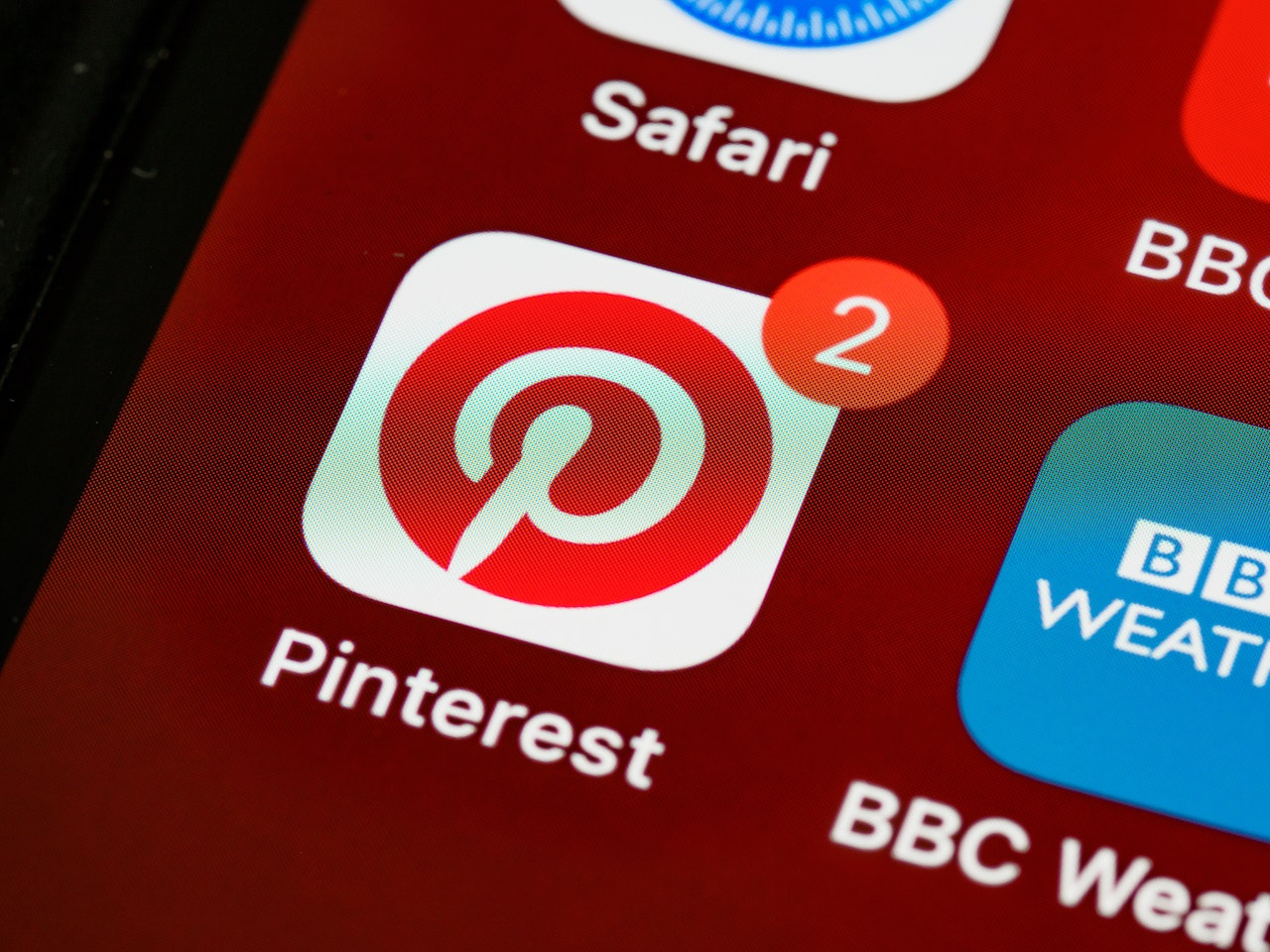 Pinterest app icon with a red notification badge showing 2 unread alerts on a smartphone screen alongside Safari and BBC Weather apps