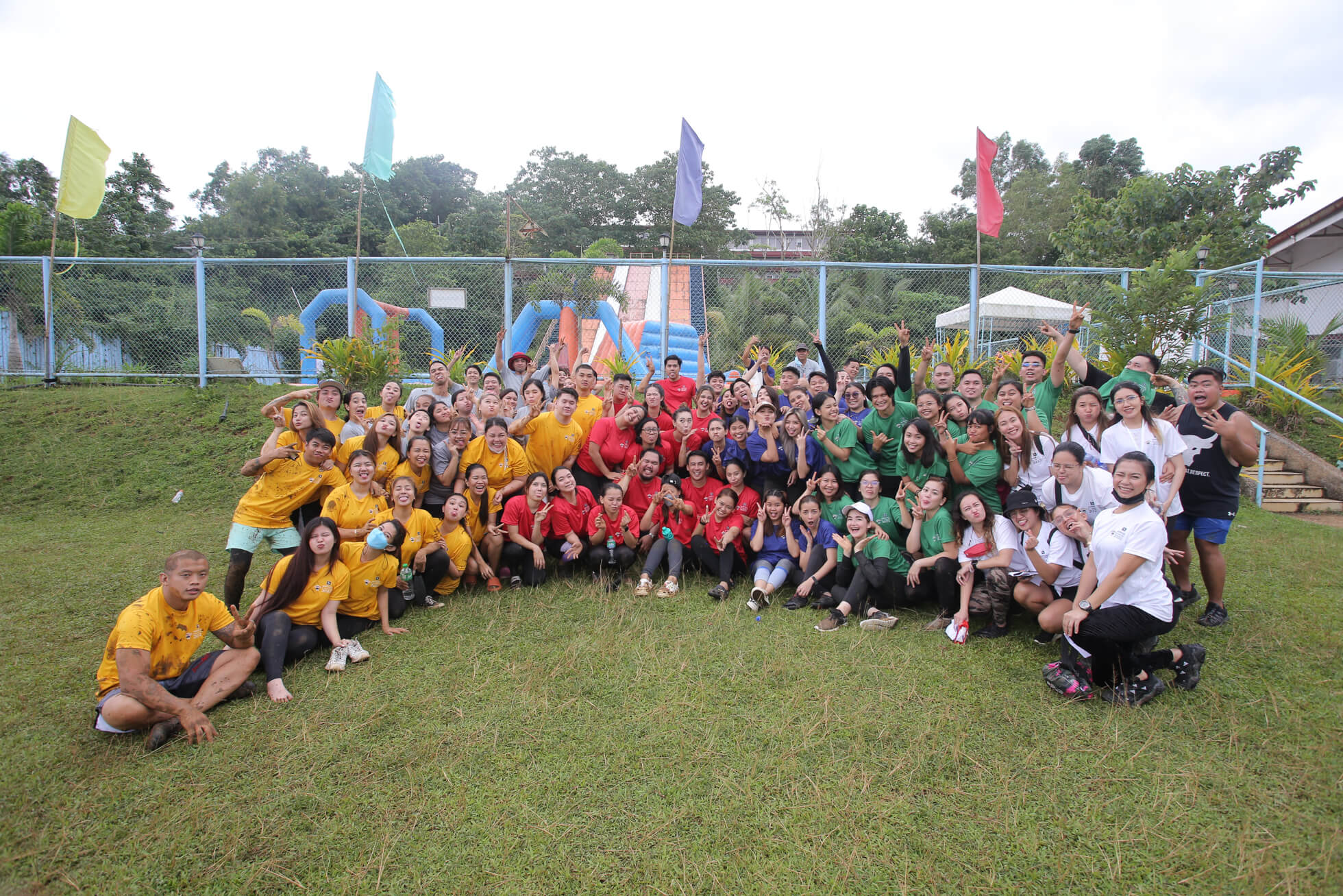Large group photo of the Somewhere team in colorful team t-shirts posing outdoors at an annual team building event