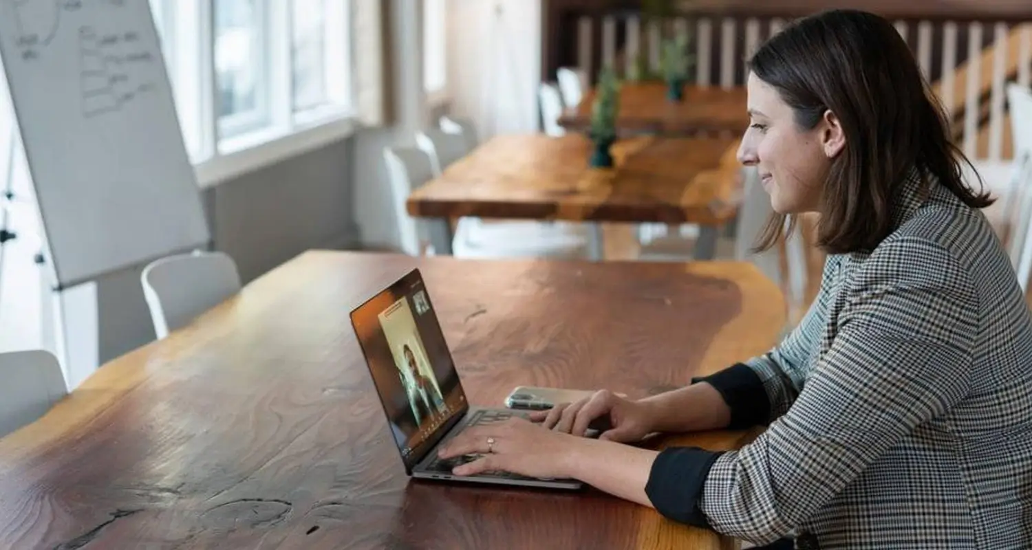 Lead qualifier on a video call with a prospect, reviewing notes at a conference room table