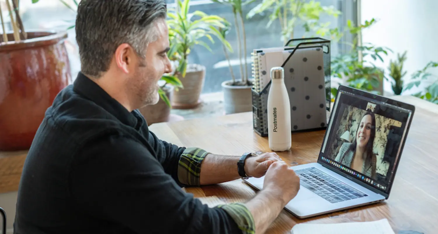Sales professional on a video call with a prospective client displayed on his laptop screen at home office