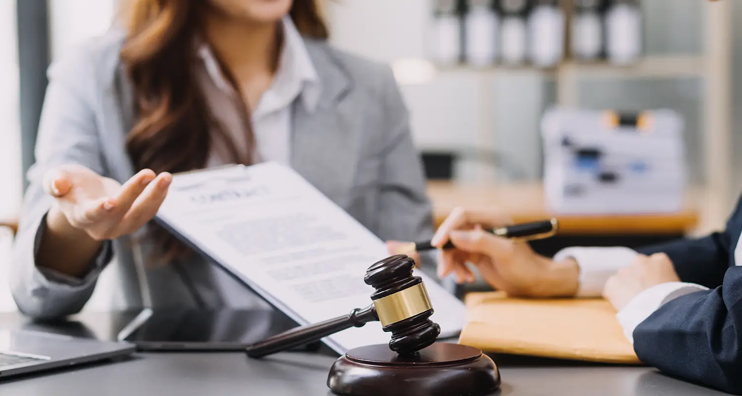 Female attorney presenting a contract document to a client with a judge's gavel on the table
