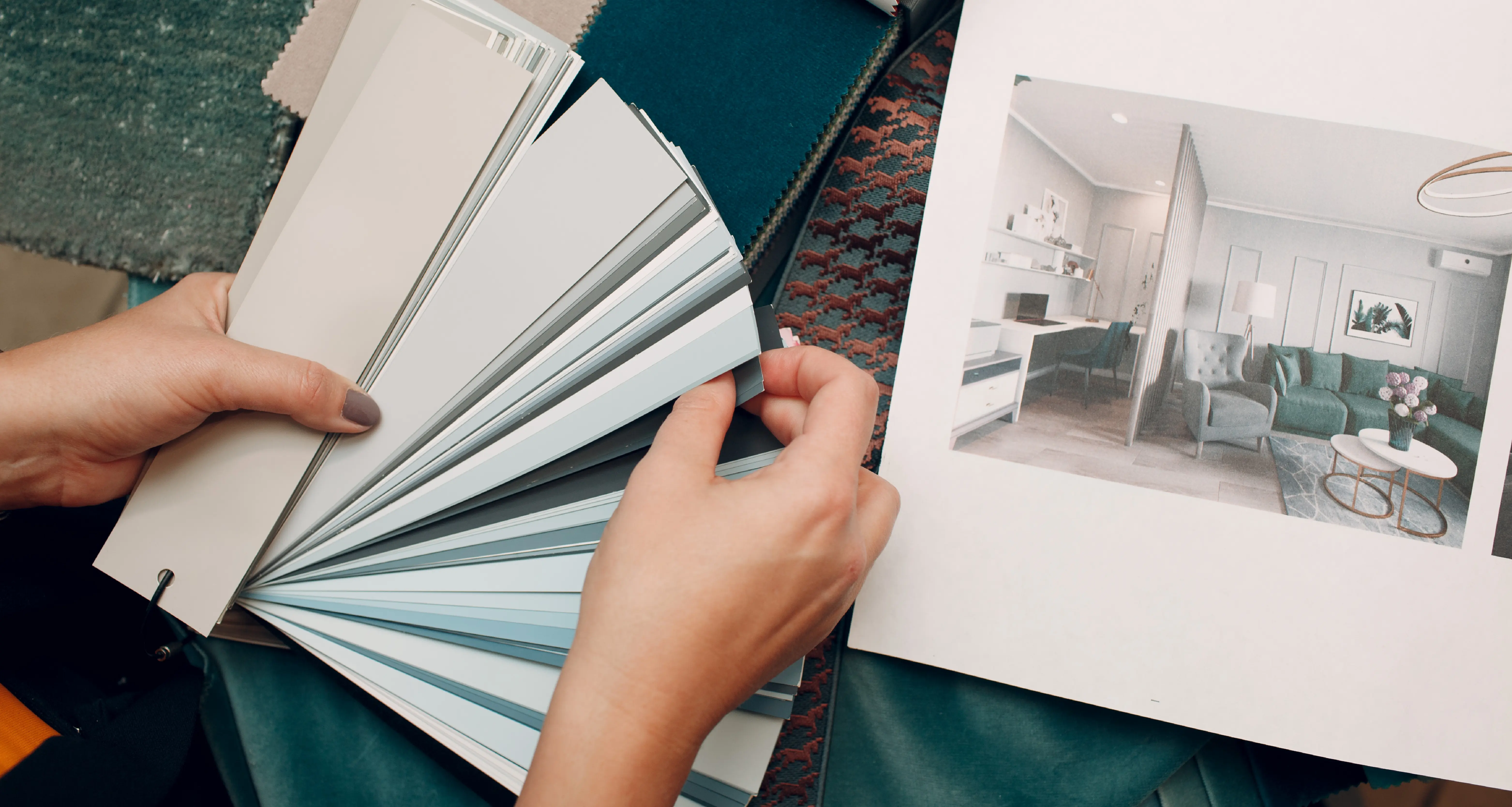 Interior designer reviewing paint color swatches alongside a room design catalog with fabric samples