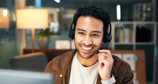Professional man with a headset smiling at the camera in a clean modern office setting