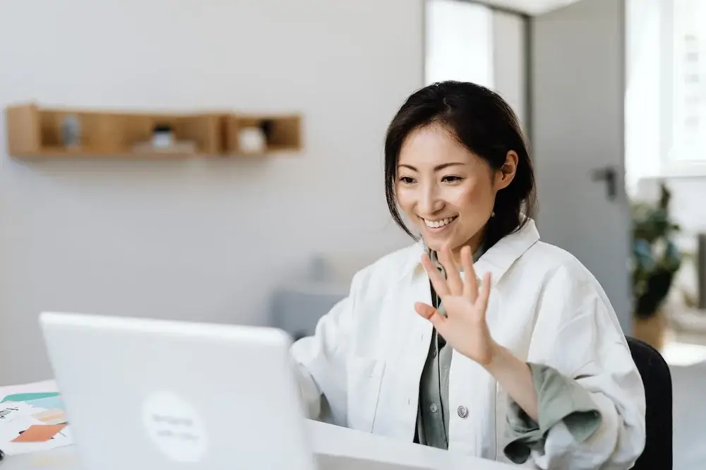 A woman smiling and saying hi during a videocall 