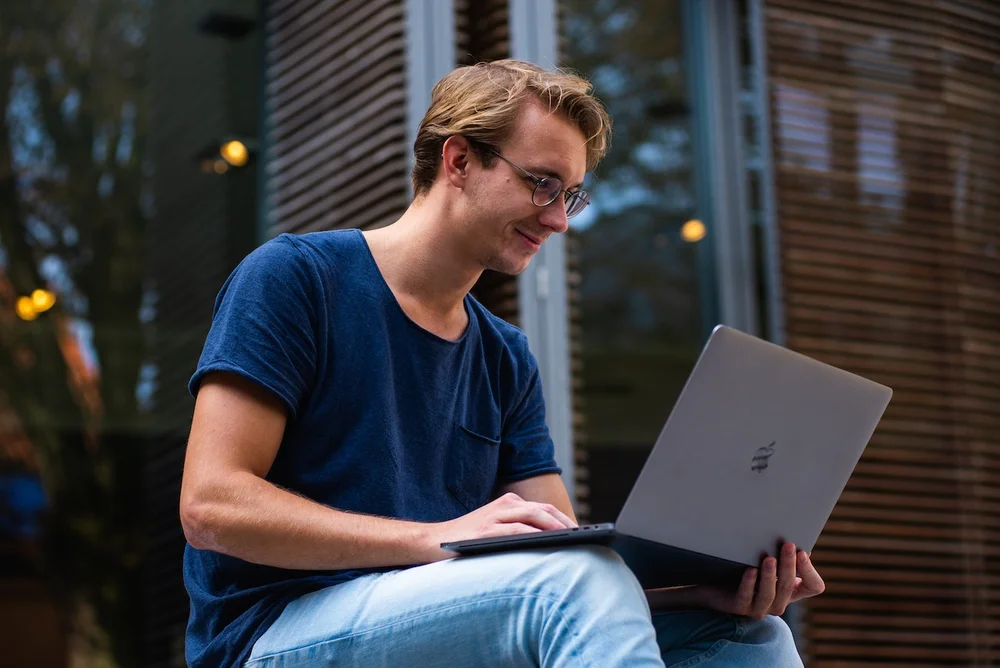 A man smiling at his laptop