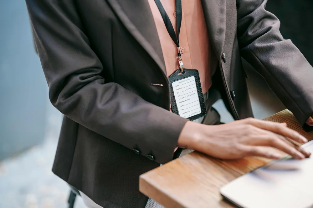 A woman wearing a lanyard working on a laptop